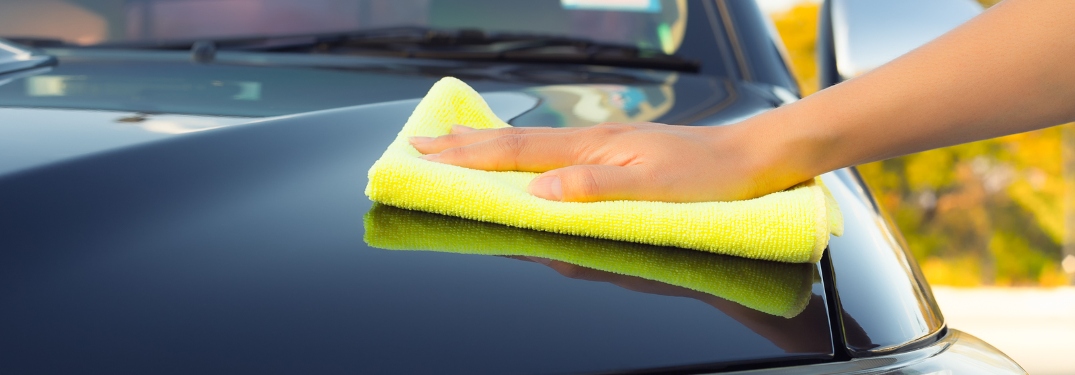 Person wiping down hood of vehicle