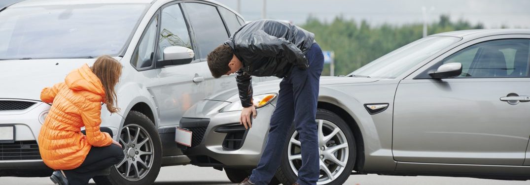 Two people inspecting the damage on their vehicles after a collision