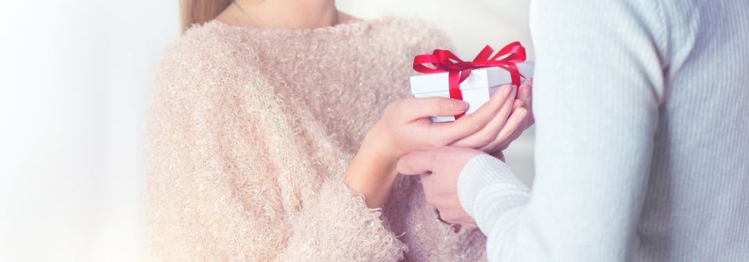 Two People exchanging a gift wrapped in white with a red bow