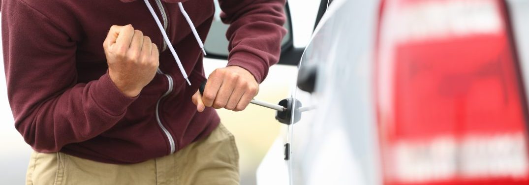 Person trying to break into a vehicle with a tool