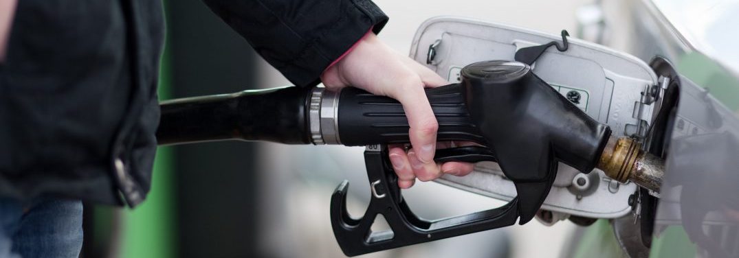 Person putting gasoline in their vehicle at a gas station