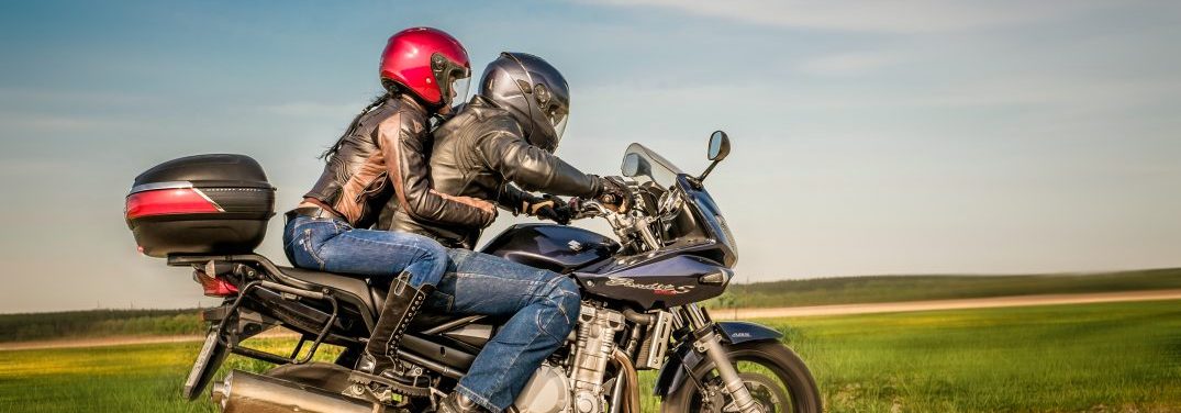 Man and a woman driving on a motorcycle wearing helmets