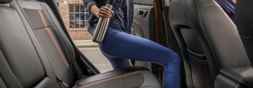 Woman getting in the backseat of the 2018 Ford EcoSport while holding a water bottle