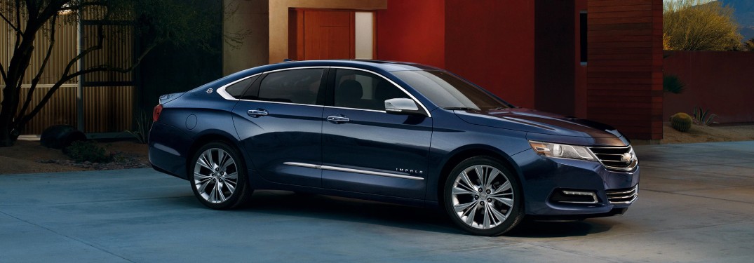 Front passenger angle of a dark blue 2019 Chevrolet Impala parked in a driveway