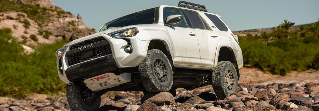 Front driver angle of a white 2020 Toyota 4Runner driving over rocks