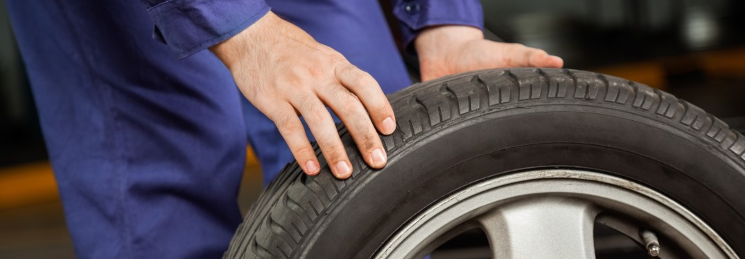 Close up of a mechanic holding a tire upright