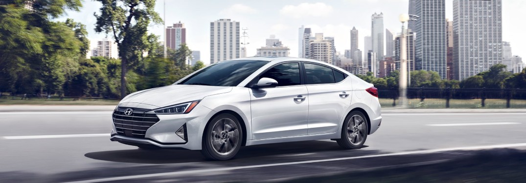 Front driver angle of a white 2020 Hyundai Elantra driving with a city in the background