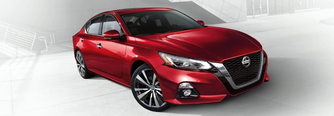 Front passenger angle of a red 2020 Nissan Altima on a white and grey background