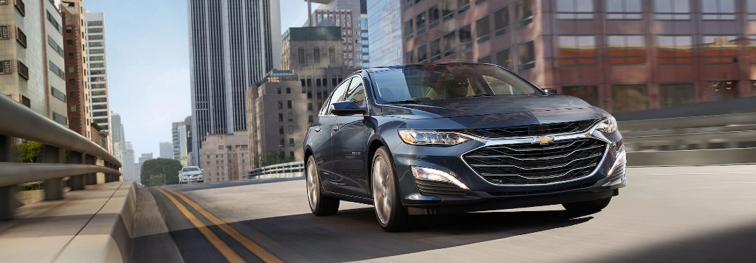 Front passenger angle of a grey 2020 Chevrolet Malibu driving in a city