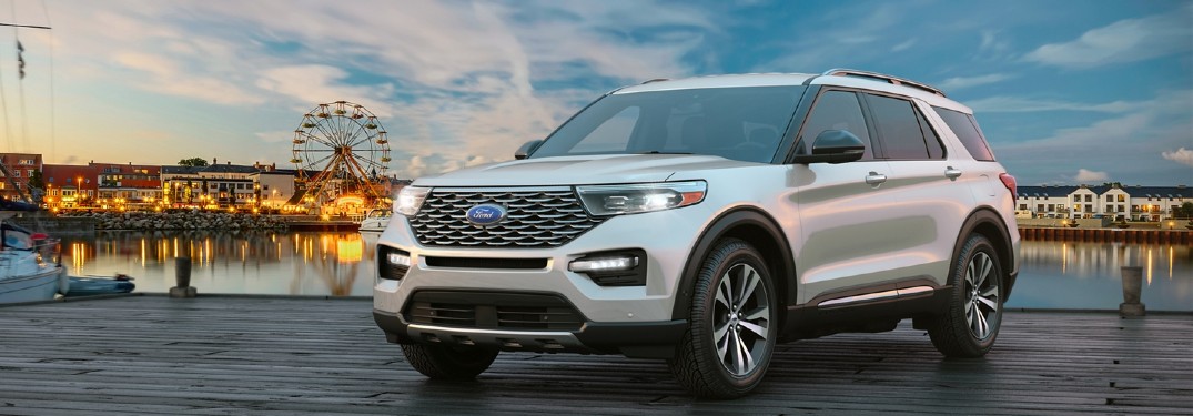 Front driver angle of a white 2020 Ford Explorer with a city and water in the background