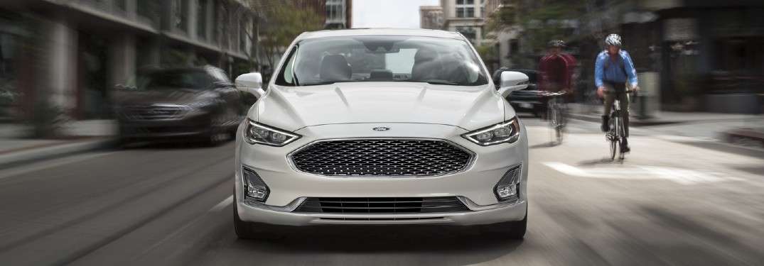 Front angle of a white 2020 Ford Fusion driving in a city