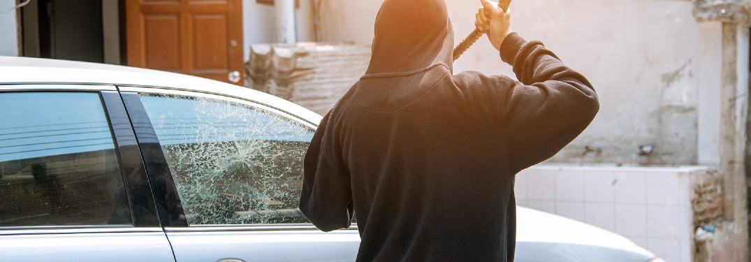 Thief breaking the glass of a car