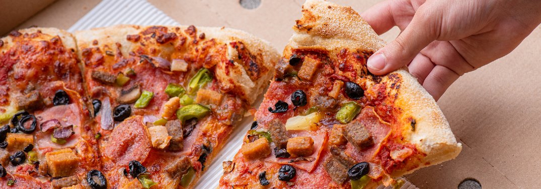 Person taking a slice of pizza