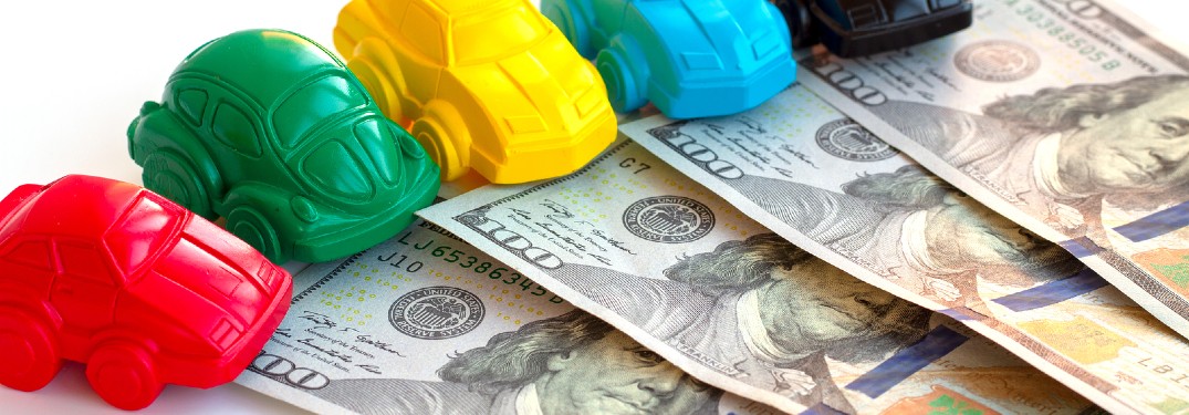Colorful toy cars on top of one-hundred dollar bills