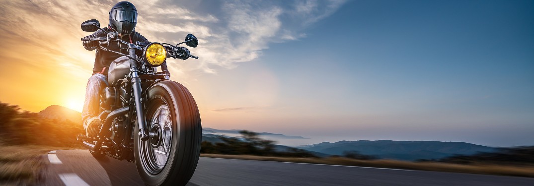Motorcycle driving on a road with a sunset in the background
