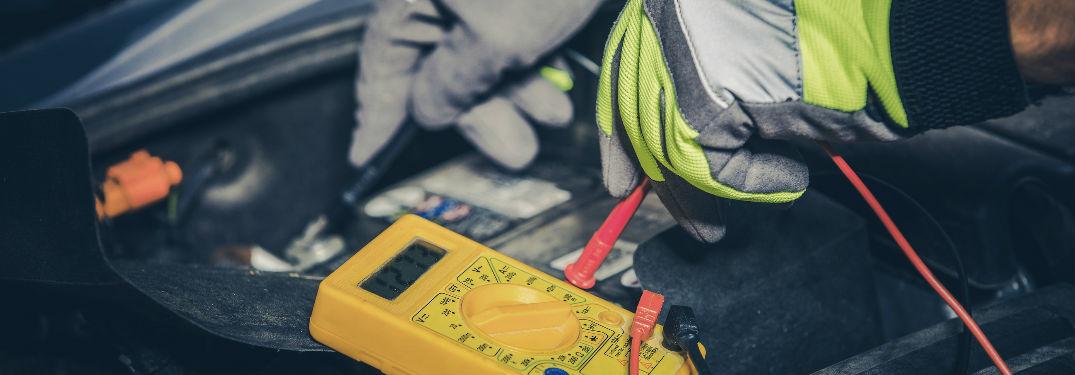 hands working on the battery under a car's hood