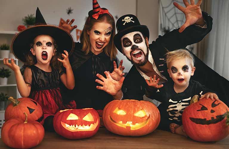 Family in Costumes with Jack-o-Lanterns at a Table
