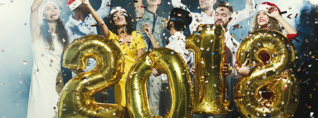 Group of people having fun while holding "2018" balloons