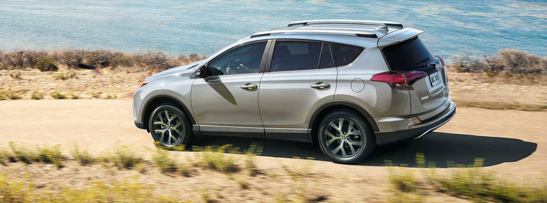 Profile view of silver 2018 Toyota RAV4 driving on dirt waterfront road