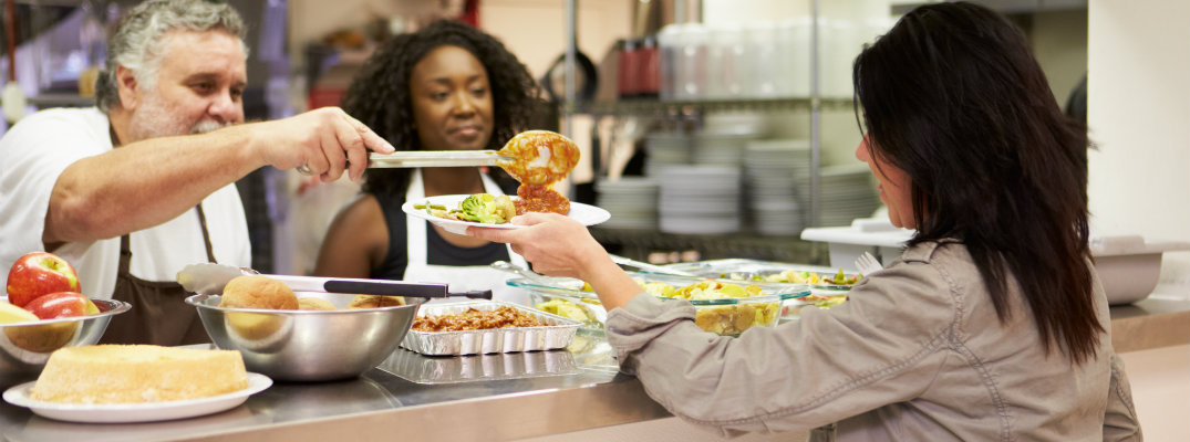 staff giving soup to woman
