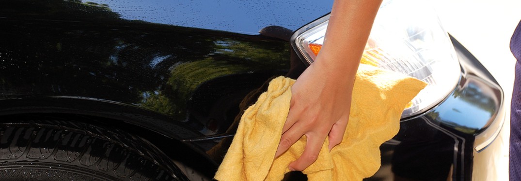 person cleaning vehicle with yellow towel