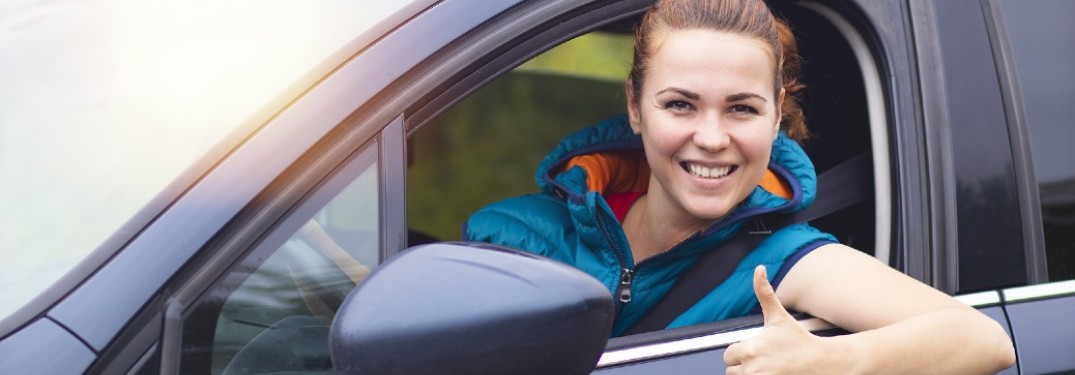 A woman in a vehicle smiling with her thumb up