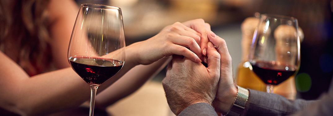 couple clasping hands next to a wine glass