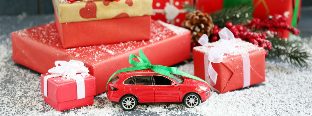 A stock photo of the a toy car in front of a stack of gifts.