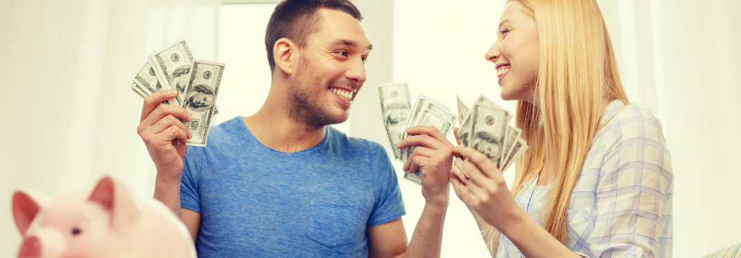 couple holding $100 bills smiling at each other