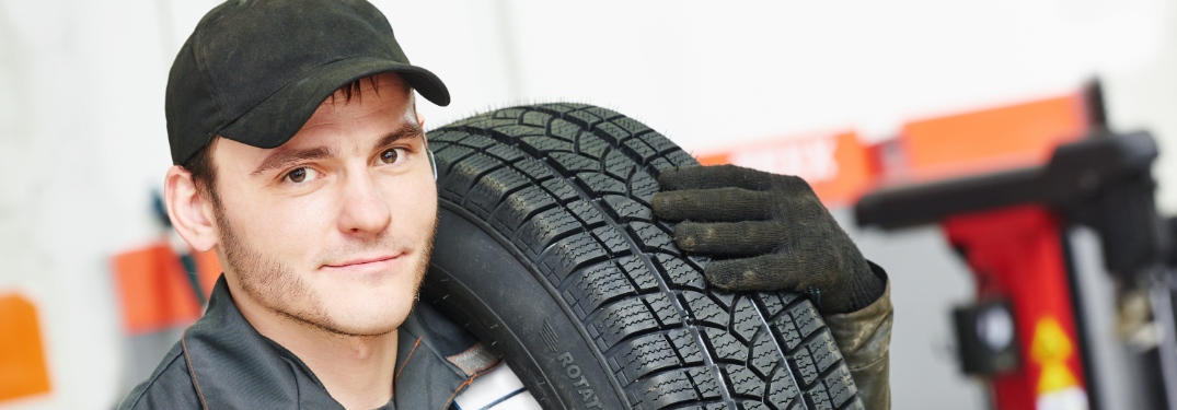 Mechanic carrying a tire in service shop