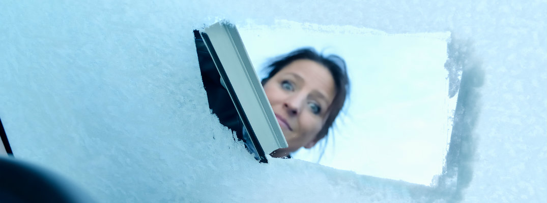 Woman scraping her vehicle's windshield