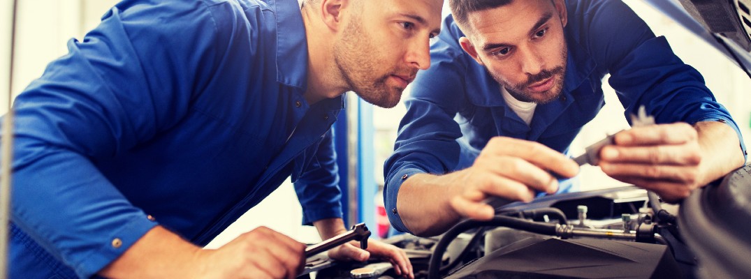 Two mechanics inspecting a vehicle engine