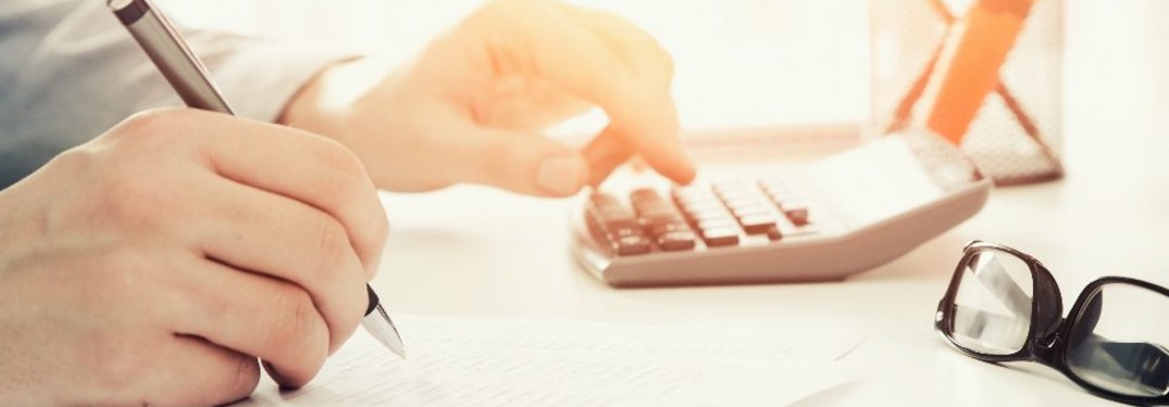 A person using a calculator and filling out a form