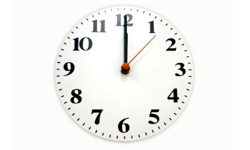 close up of clock with white face black numbers and red second hand