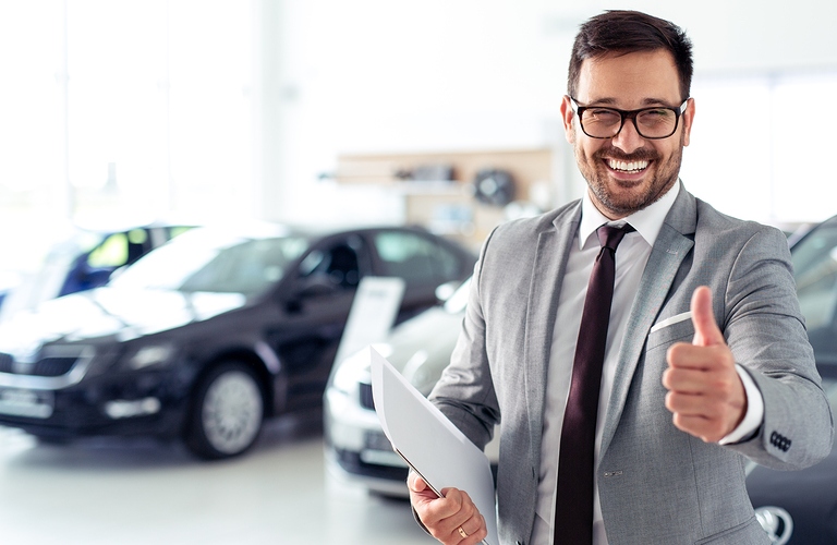 Happy car salesman in front of vehicles