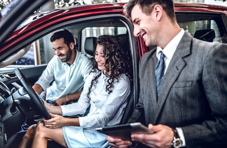 Salesman looking at a vehicle with a couple
