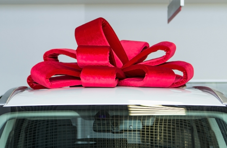 Big red bow on top of a vehicle