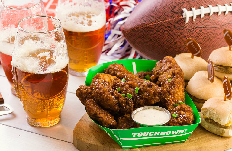 Close Up of Wings, Beers, Burgers and a Football on a Table at a Party