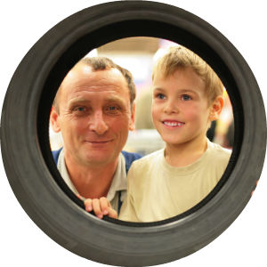 Child and Mechanic Looking Through a Tire
