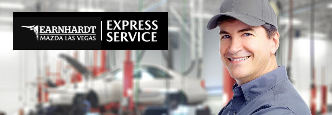 Young Mechanic Smiling in Garage with White Earnhardt Mazda Las Vegas and Express Service Logo Text on Black Background