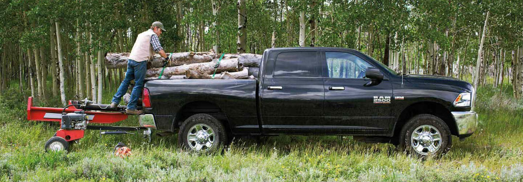 Man loading logs into the bed of the 2018 Ram 2500