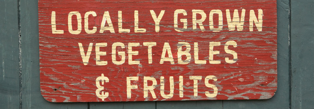 Locally grown vegetable and fruits, text on a red wooden background