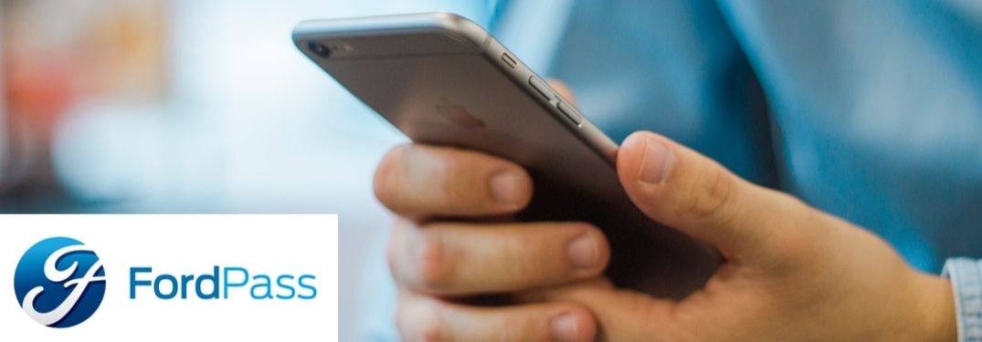 FordPass logo with closeup of man's hands holding smartphone