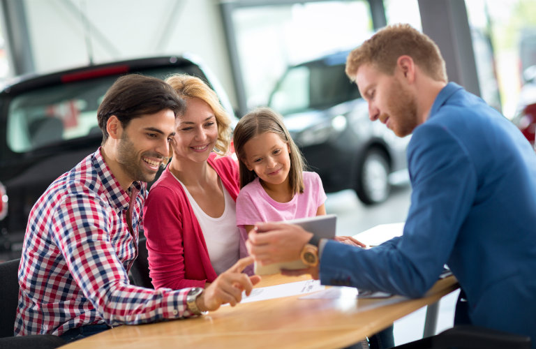 family at dealership talking to salesman