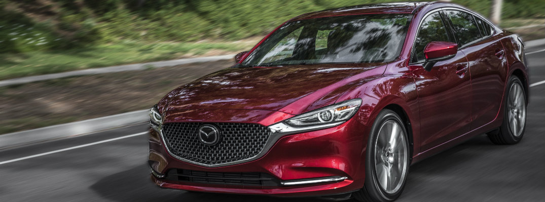 2018 Mazda6 red coat paint finish driving down road next to green forest hill