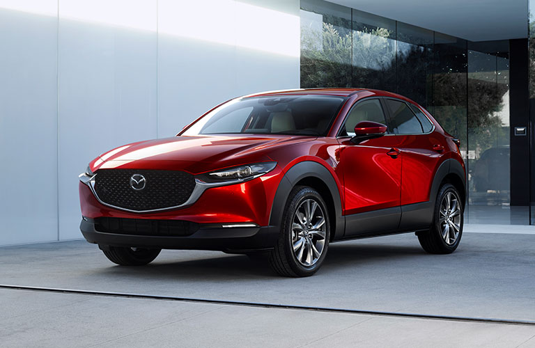 A red 2020 Mazda CX-30 parked in a parking lot next to a concrete building.