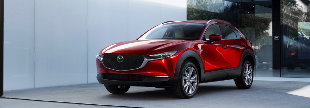 The front and side image of a red 2020 Mazda CX-30 parked near a concrete wall.