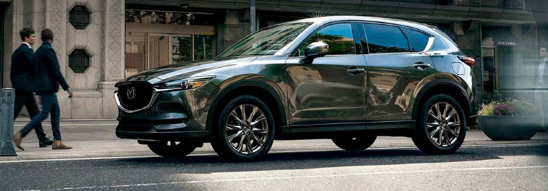 A gray 2020 Mazda CX-5 driving down a city road.