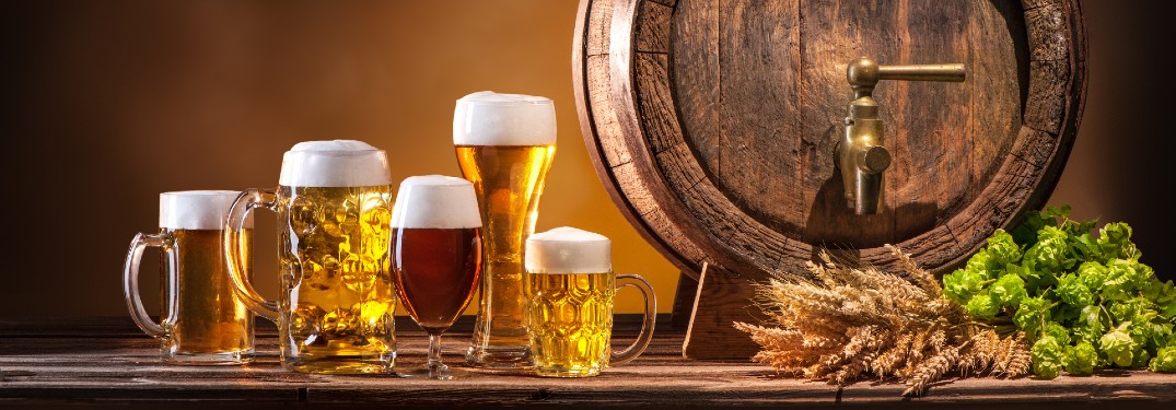 An image of several mugs of beer with an Oktoberfest beer barrel next to them.