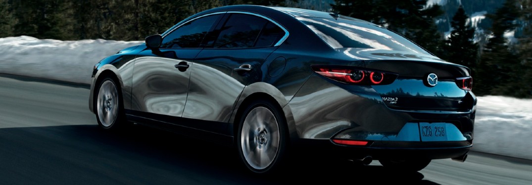 The side and rear view of a gray 2021 Mazda3 Sedan driving in winter weather.